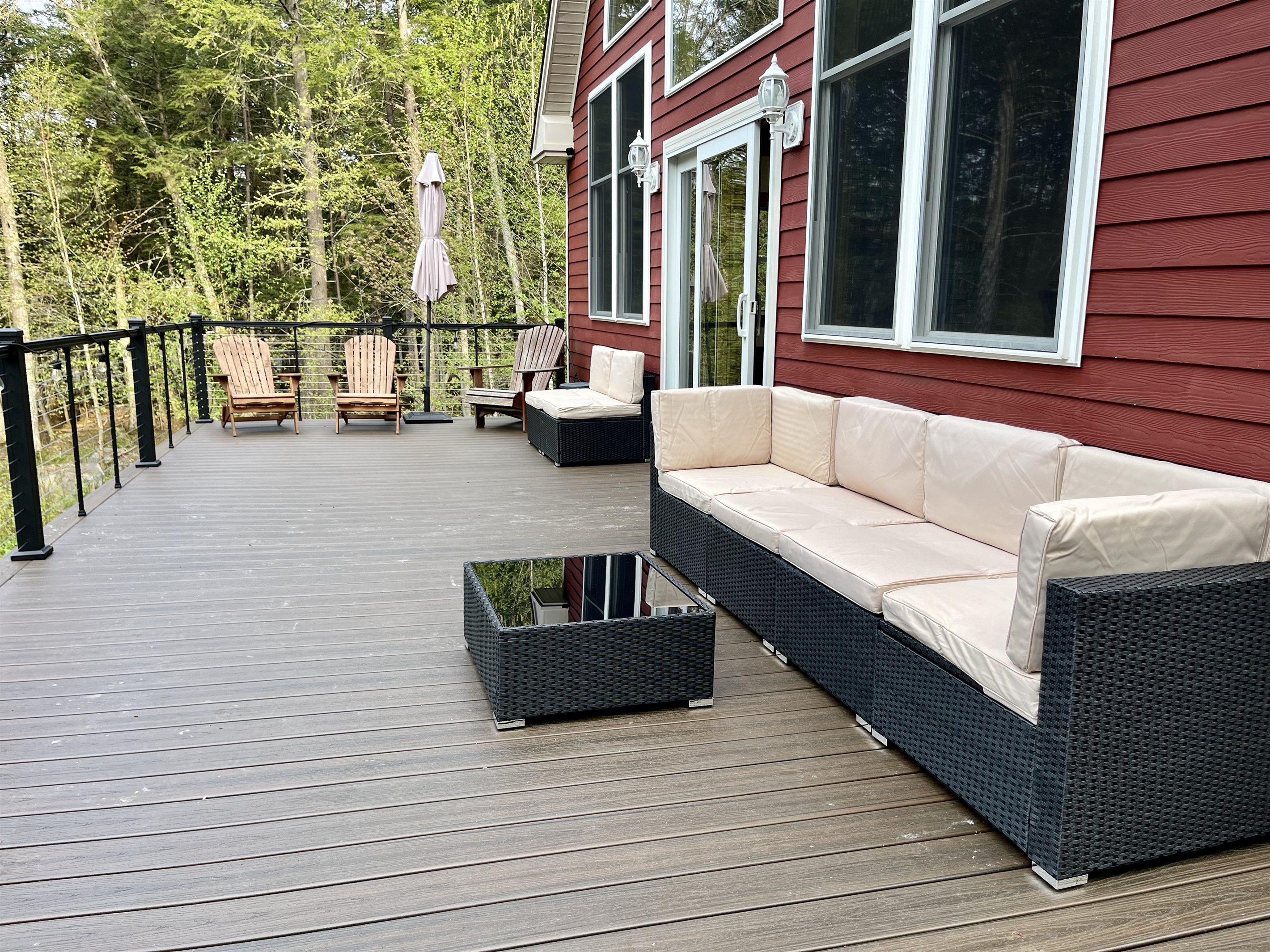 Deck overlooking the lake with outdoor furniture, umbrella, and solo stove.