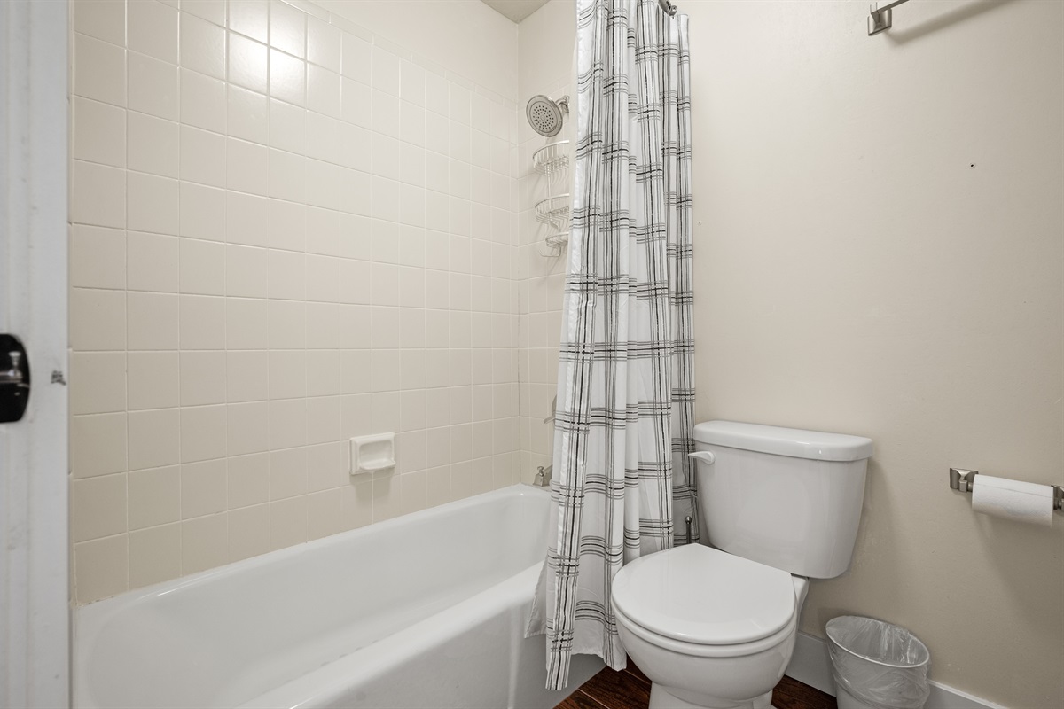 Combination shower and tub with tiled walls.