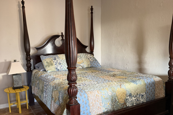 This comfortable apartment bedroom combines traditional style with tropical charm. The highlight is an elegant carved four-poster bed.