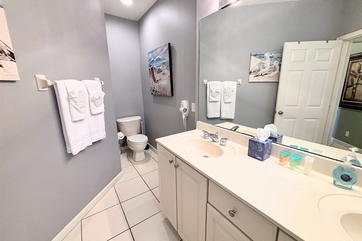 Clean and spacious bathroom with large vanity, tile flooring, and bright mirror lighting.