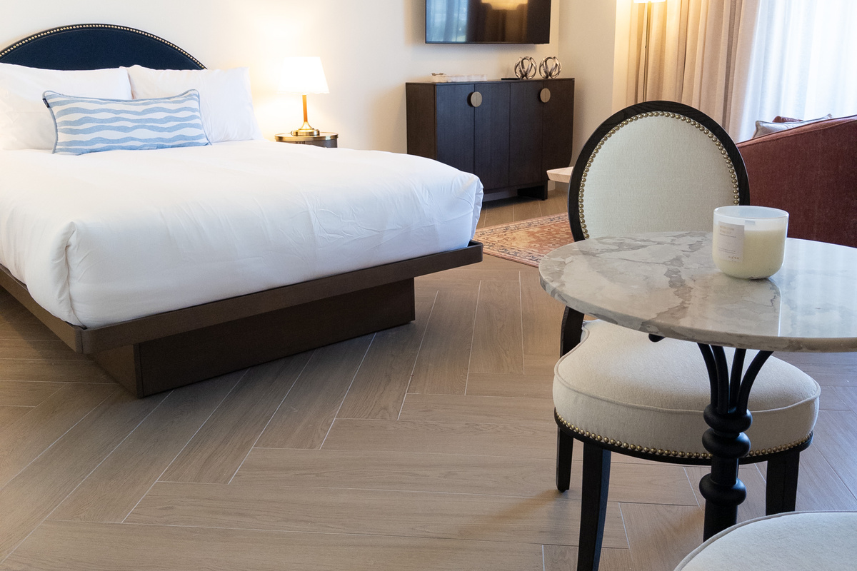 Restful bedroom - layered bedding, a marble bistro table and warm wood floors.