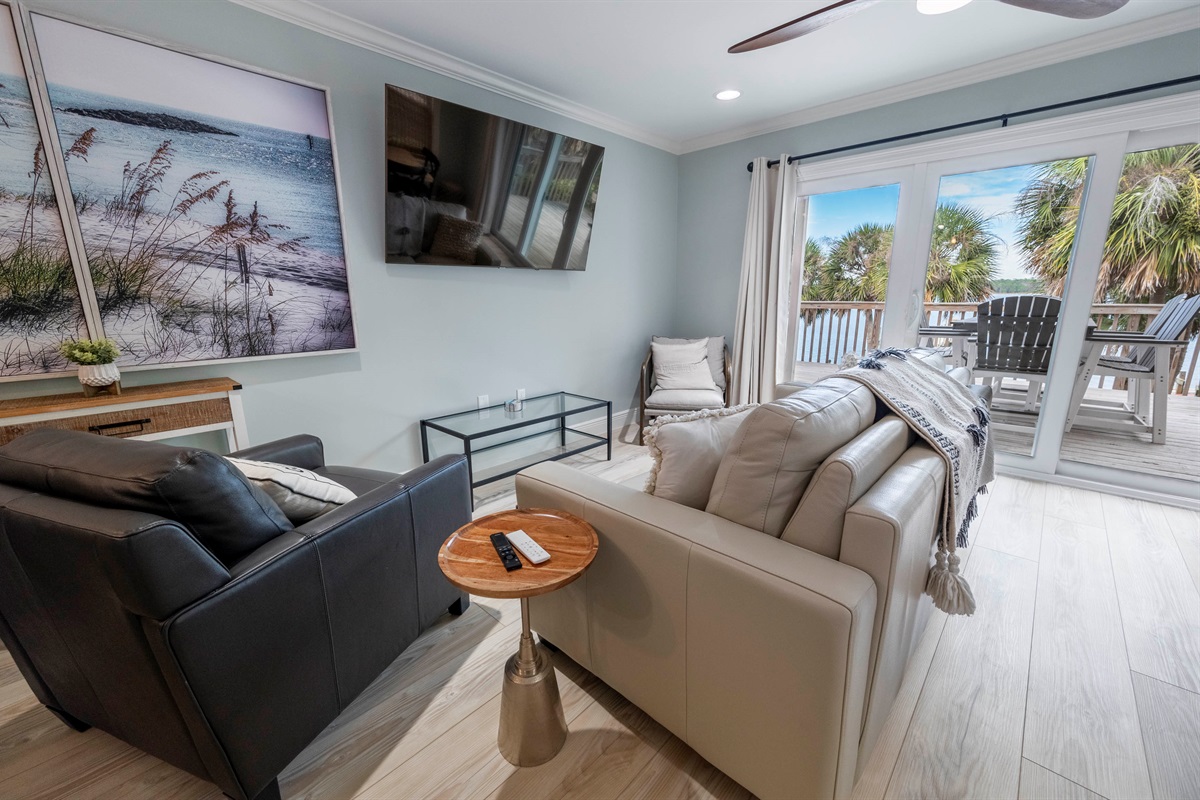 Relax in a modern beachside living room with cozy decor and balcony views at “Gone Coastal,” Laguna Bella, Gulf Shores, AL.
