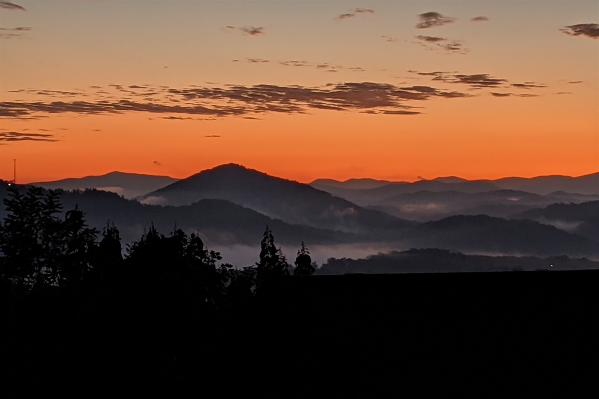 - Fiery sunset painting the Smoky Mountain skyline with warm orange hues   - Evening calm settles as golden light fades behind distant ridges   - The perfect end to a day surrounded by mountain peace and beauty