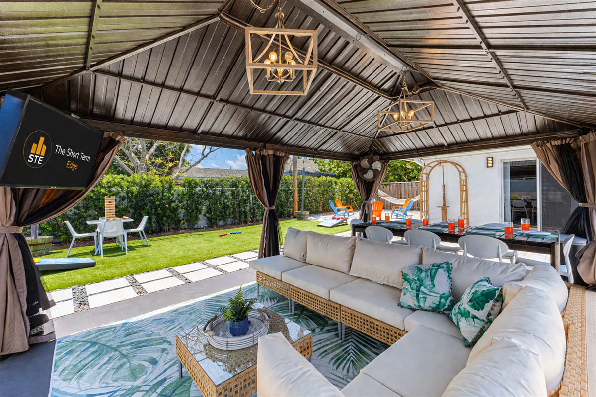 Outdoor Smart TV, comfy couch, and industrial fan — backyard game nights made easy!