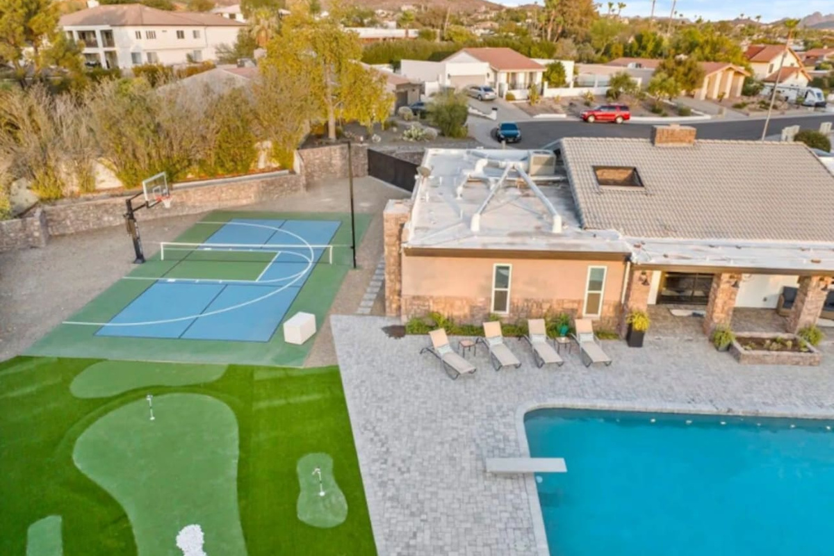 From above: putting green, sport court, pool, and mountain backdrop — a backyard built for every kind of fun.