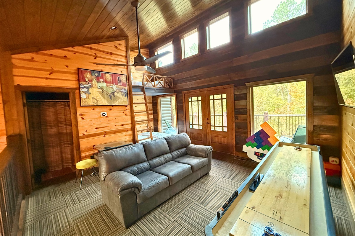 Bright open-concept cabin interior with seating area and tall windows bringing in forest light.