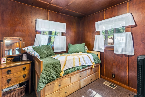 Bedroom 2 features a twin trundle bed and warm wood walls, offering a cozy space to rest and recharge.