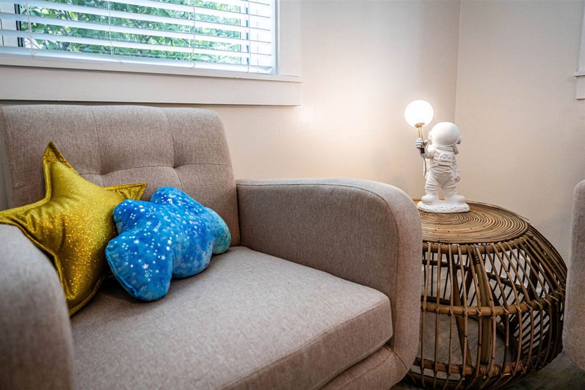 Cozy single sofa by the window, accented with a cute astronaut figurine on the side table, adding a playful touch to the space.