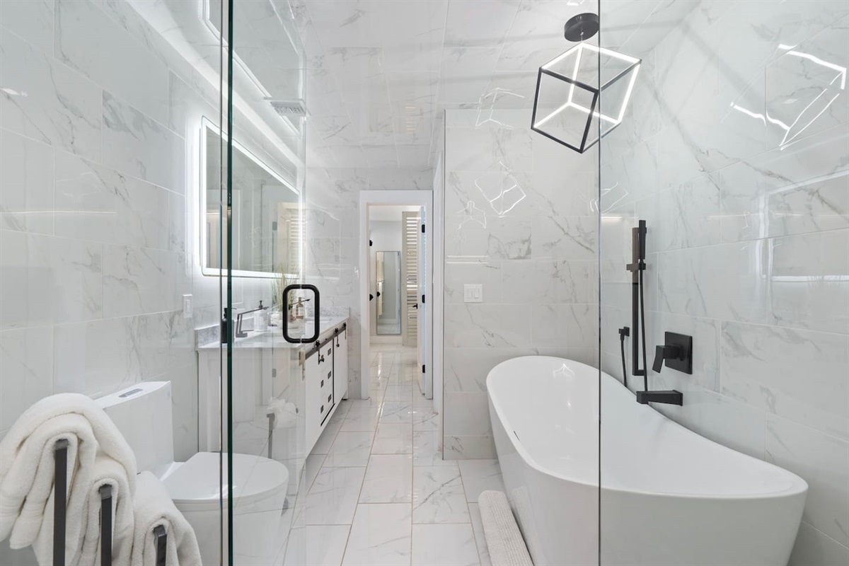 Wide-angle view showcasing the elegant tub, vanity, and entry to closet.

