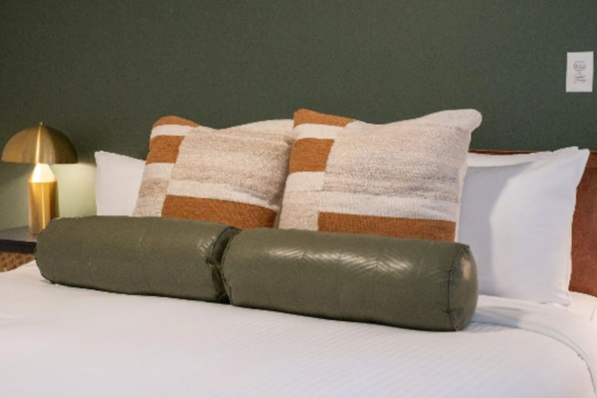 A brass lamp and deep green wall bring warmth and texture to this quiet corner of the bedroom.