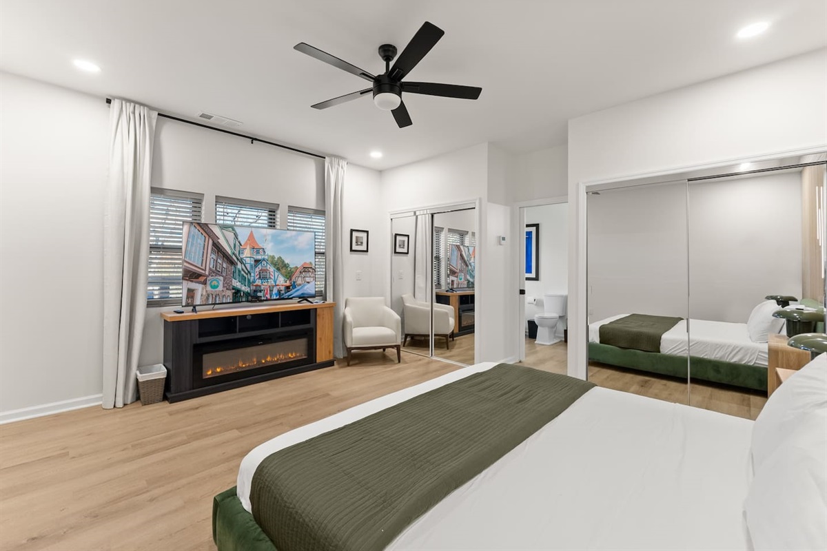 Master bedroom with a king bed, cozy electric fireplace, and a large TV—perfect for relaxing in comfort.