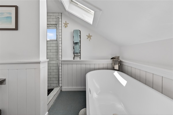 Upstairs full bath features classic penny tile flooring, a walk-in shower, and a large soaking tub perfect for relaxing after a day at the beach.