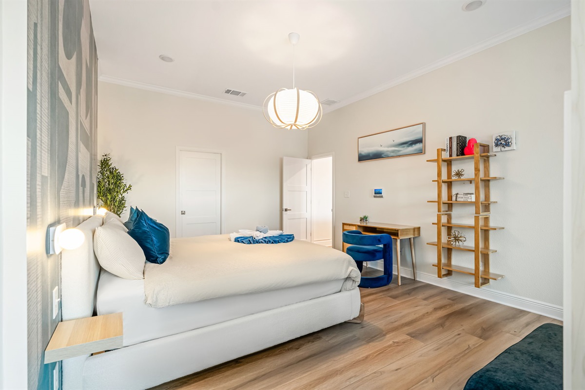 Another view of the luxurious primary bedroom with comfortable king bed and warm lighting.