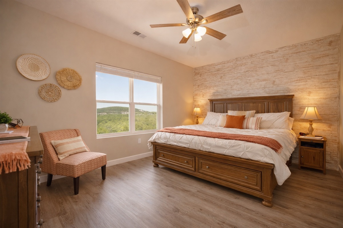 Bright and spacious king bedroom with cozy layered bedding and beautiful hill views