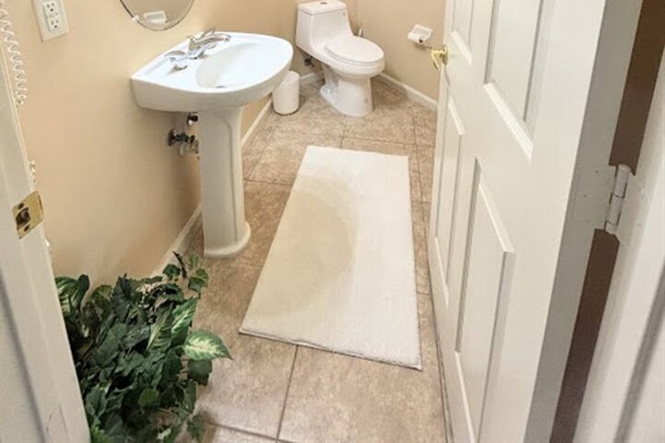 Convenient half bathroom with pedestal sink, tile flooring, and clean neutral finishes.