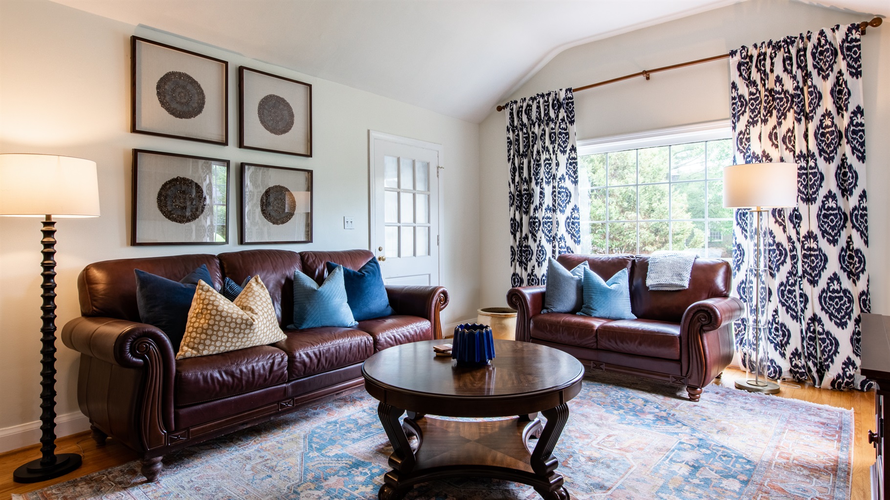 Unwind in this stylish Louisville living room on the Kentucky Bourbon Trail. Relax on leather sofas with blue pillows, enjoy natural light, and admire the classic decor.
