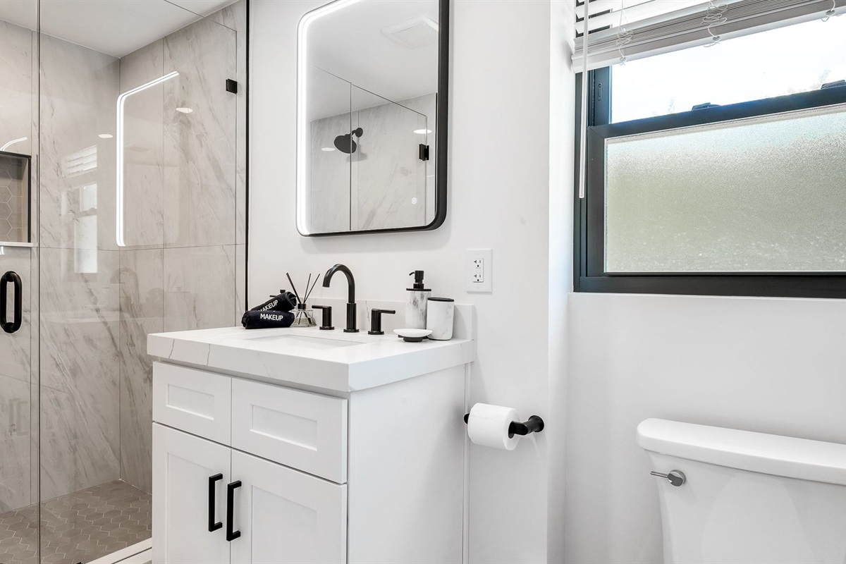 Step into a brand-new, spa-inspired primary bathroom featuring a sleek glass-enclosed walk-in shower with rainfall showerhead, designer vanity with LED mirror, and elegant finishes throughout.