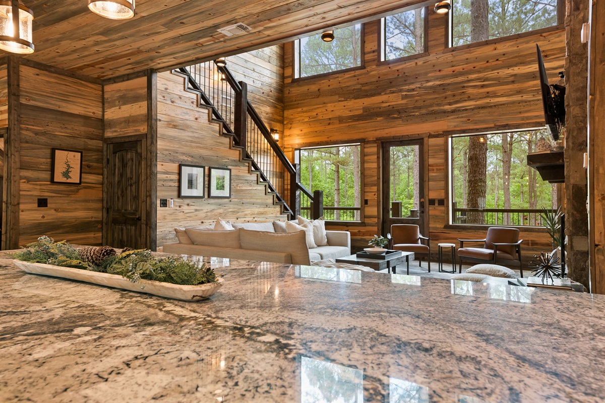From the granite kitchen island, the view extends into a spacious living area with soaring ceilings and abundant windows