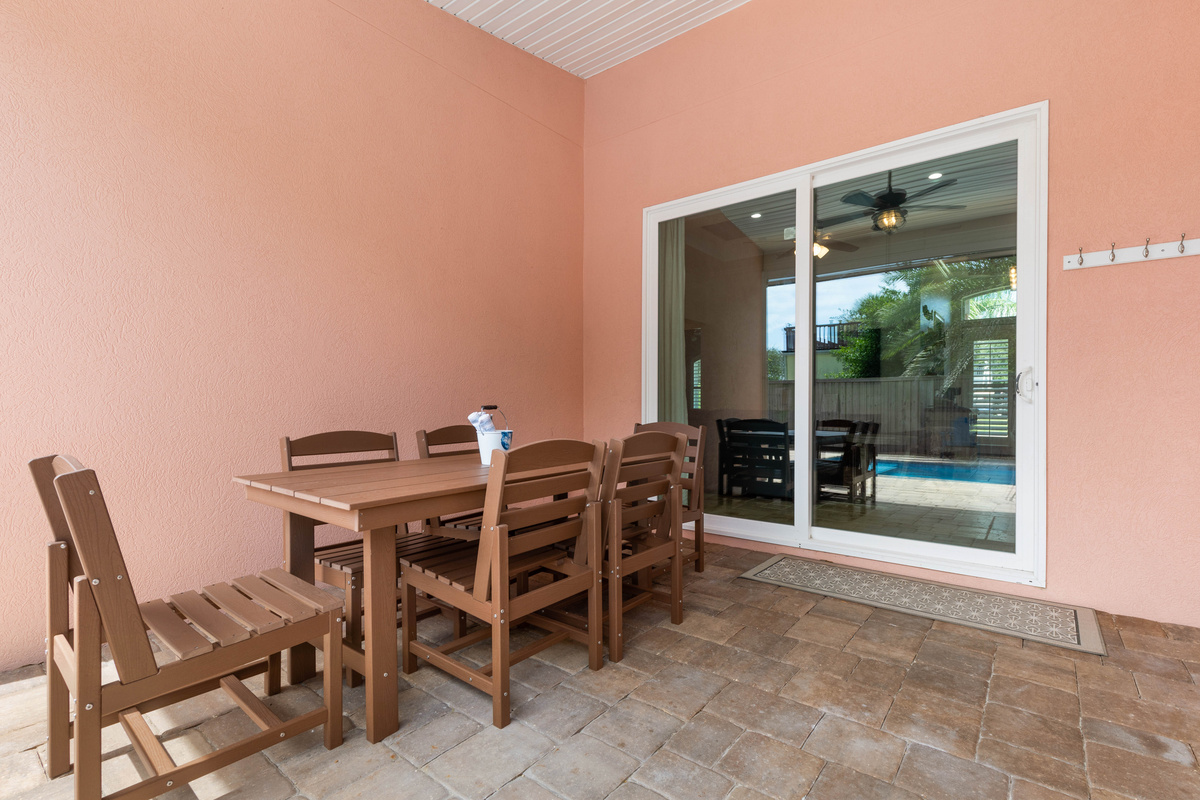 Outdoor dining sits just outside the sliding doors, with wall hooks for hats and towels as everyone heads back in.