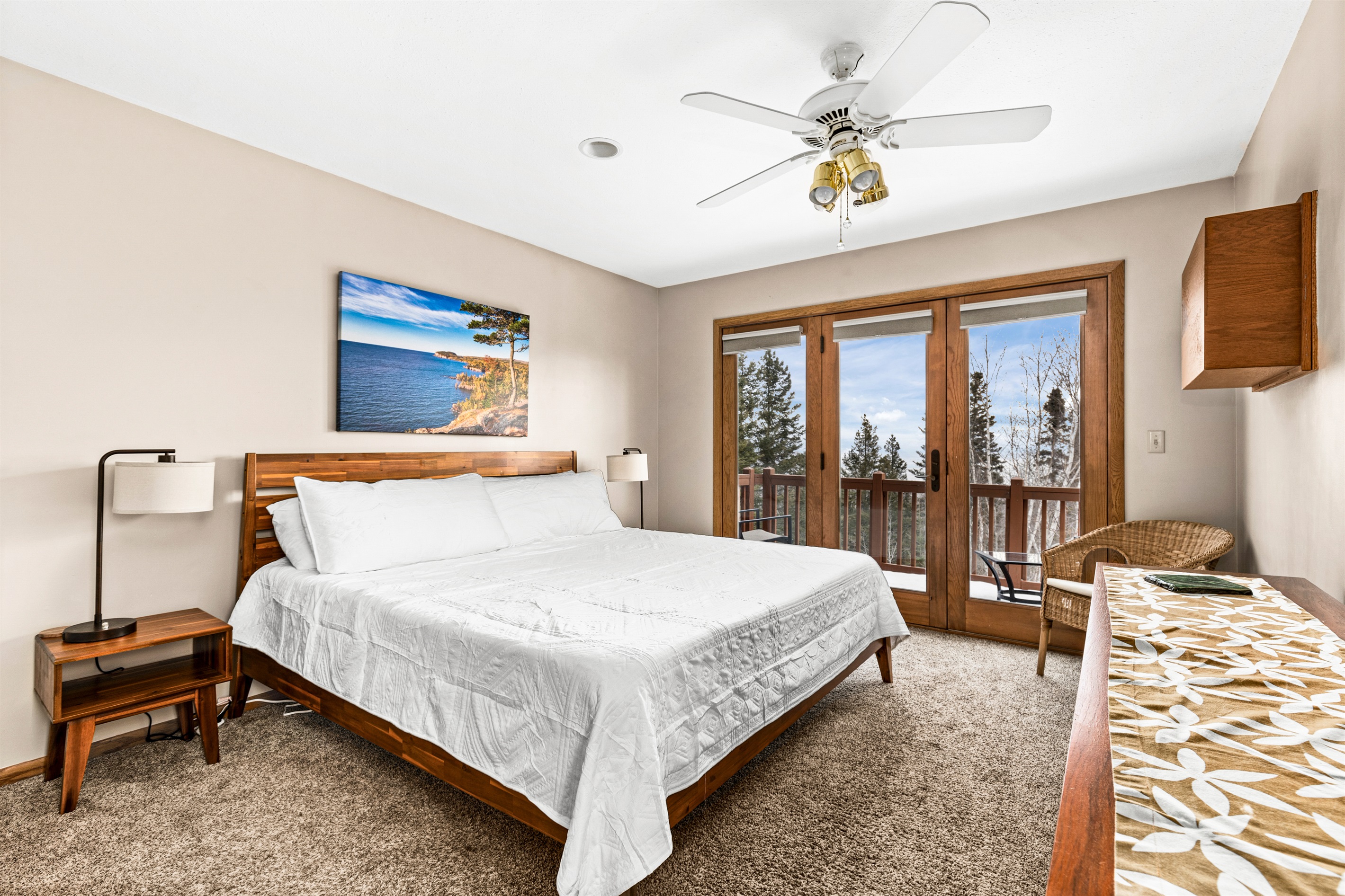 Serene primary bedroom upstairs featuring a plush king bed, large windows with breathtaking Lake Superior views, and access to a private deck. This tranquil retreat offers the perfect blend of comfort and natural beauty.