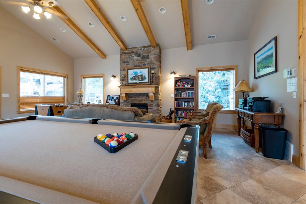 Bright and open community game room with a mountain lodge feel and a pool table.