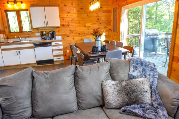 Dining table for 10 with overflow seating on the deck. This room is filled with natural light boasting in from the 2-story cabin windows, and 10-foot slider doors that lead outside to the expansive deck. 