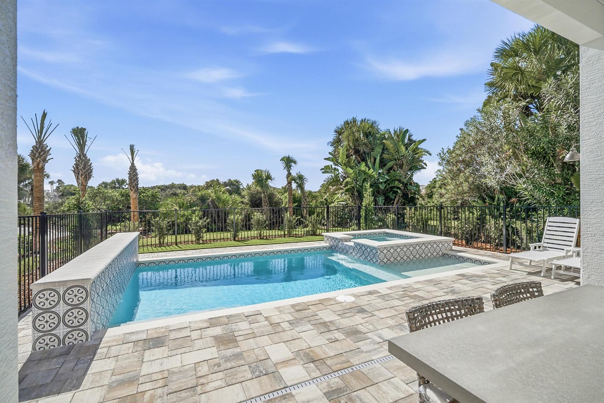 You step out with your morning coffee, the pavers still cool, and the pool glassy as the sky. A quick dip, then the spa bubbles while palms sway beyond the fence—your own private oasis between beach adventures.
