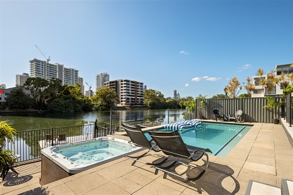 Resort-style pool & spa with tranquil canal outlook and Surfers Paradise skyline beyond.