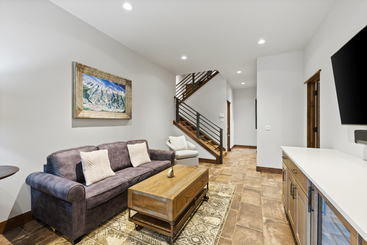 Lower level living area with large tv, wine refrigerator and Queen sofa sleeper. A full-sized twin bed is stored nearby (not shown) and can fit easily in this area. 