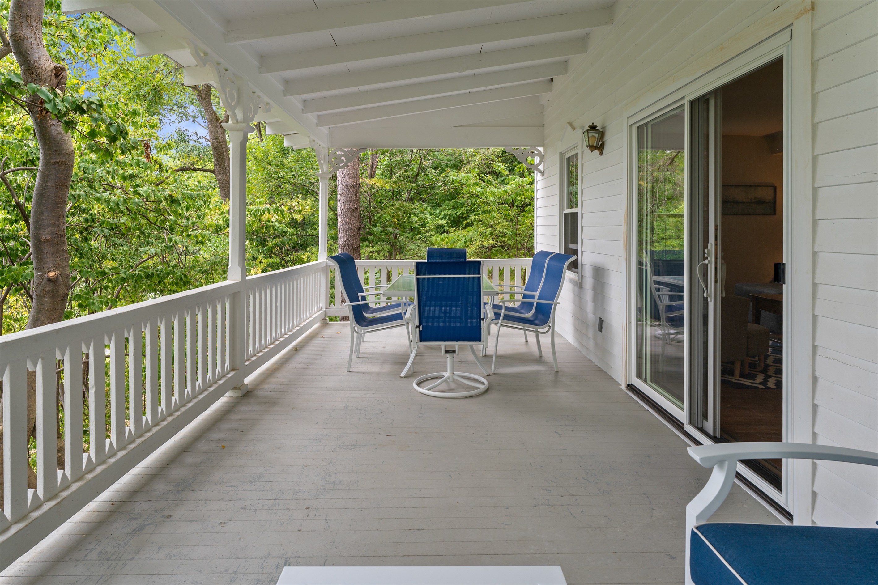 Charming covered porch surrounded by trees, perfect for relaxing with morning coffee or outdoor dining.
