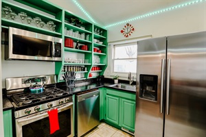 A green and black kitchen fully equipped with complete utensils, blending modern design with practicality for culinary excellence.