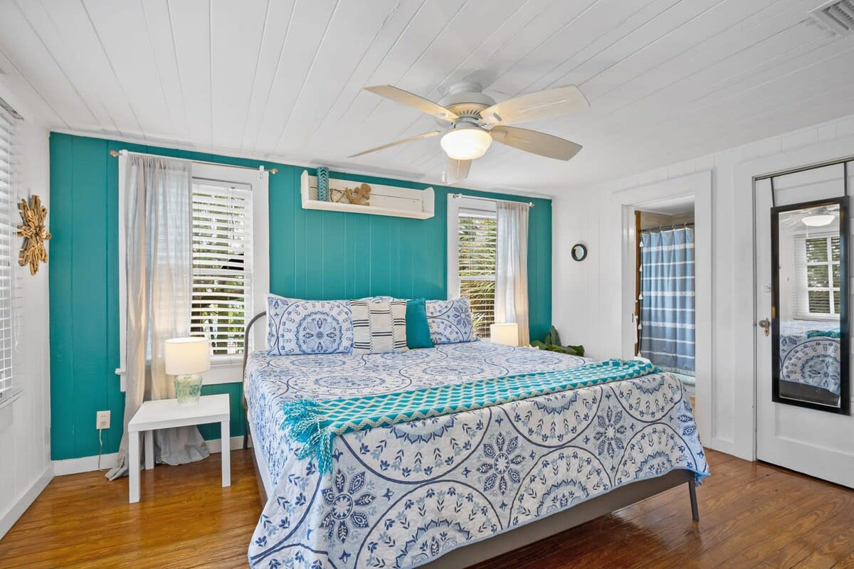 The bedroom keeps the same easy blue and white palette, with a king bed sitting under a slowly turning ceiling fan. Plantation shutters mean you can sleep as late as the holiday will let you get away with sleeping.