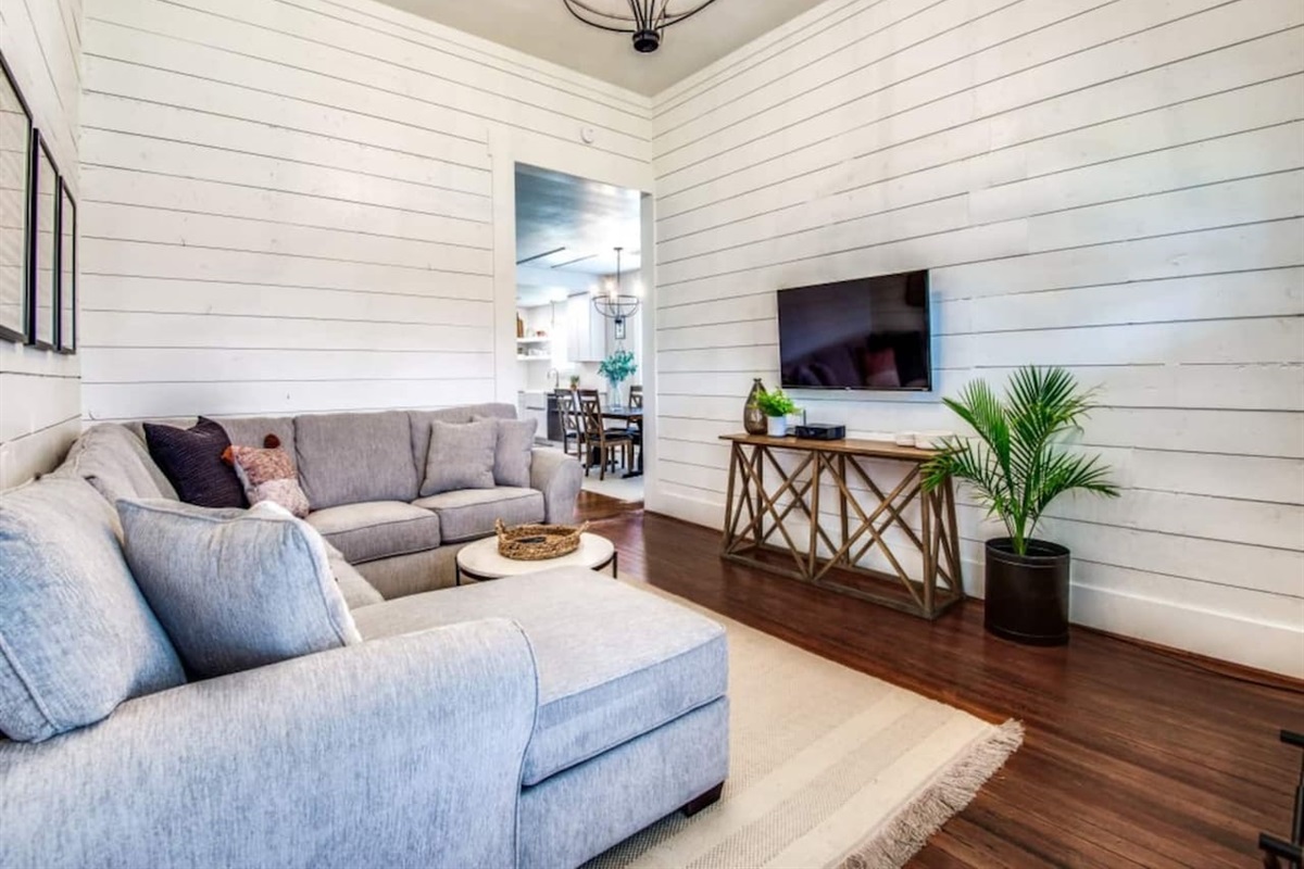 Shiplap accent wall, Smart TV, gray sectional, hardwood floors, and decorative chandelier. Modern farmhouse Airbnb in Aubrey TX sleeping up to 7. Minutes to The Milestone, Morgan Creek Barn, Lake Ray Roberts, and 30 min to Frisco.