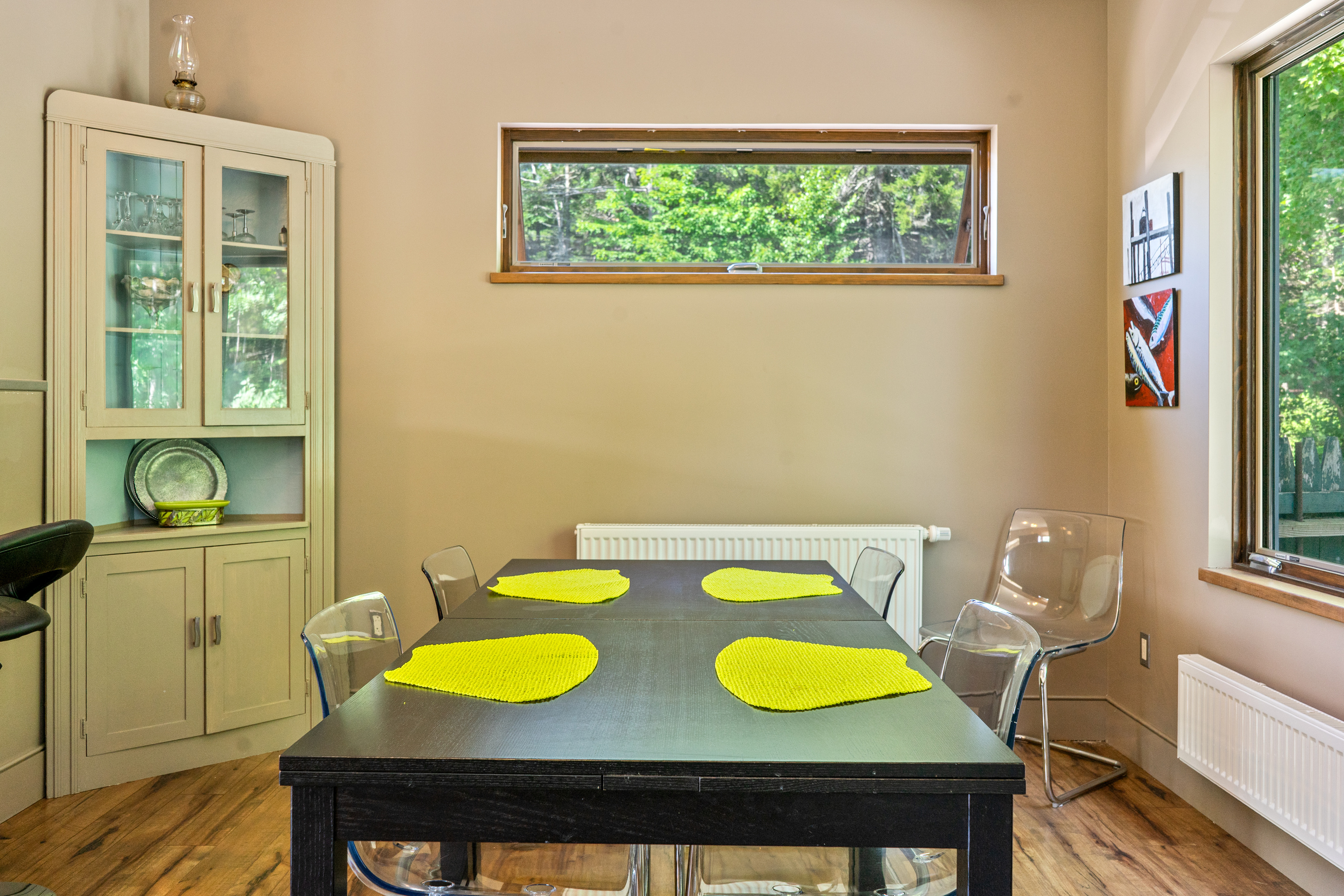 Spacious dining area with seating for six, plus additional breakfast bar seating for two. Large windows overlook the massive backyard, 33ft deck, and fire pit area, perfectly blending indoor dining with the Acadia wilderness outside.