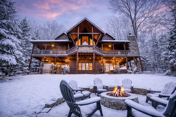 SNOW! The back of the beautiful "Blessed Sunset" mountain retreat home overlooking the back yard! Stunning A-frame, wrap-around porch, screened-in patio, outdoor fireplace, outdoor dining table, sauna, hot tub, outdoor couch, and more!