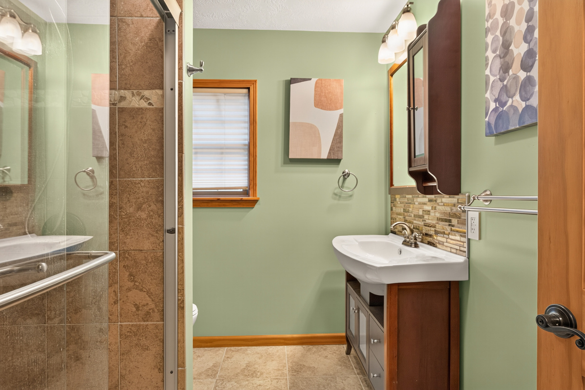 Shared bathroom with tiled shower and vanity