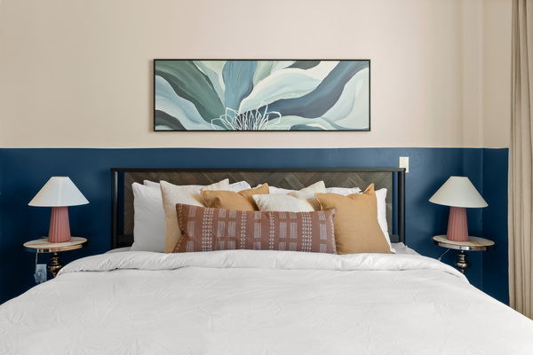 Firm king bed styled in soothing desert-modern tones with bespoke headboard and layered pillows.