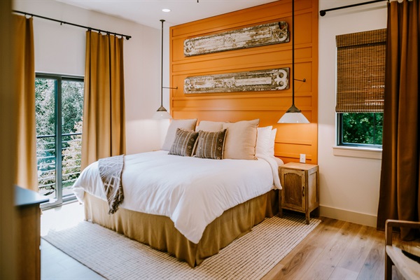 Cutter's Quarters Bedroom #2 &mdash; a pillow-top king with a custom arched headboard and warm modern Western styling, included in your Gaines Ranch on the Square group reservation.