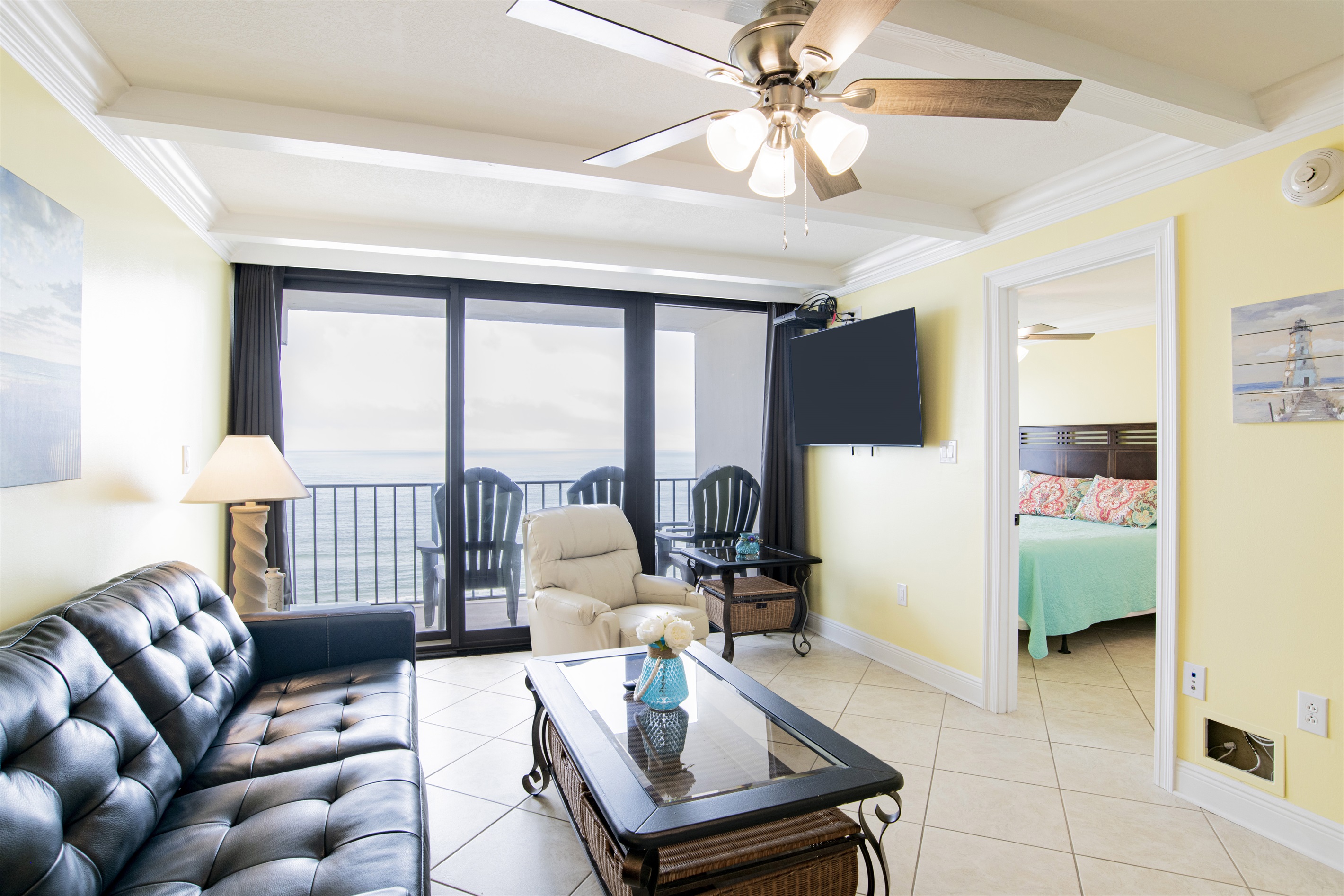 Living Room with A Great View. It Has A Queen Size Leather Sleeper Sofa, 2 Swivel/Rocker Recliners, 3 End Tables, A Coffee Table, A 58" Wall Mounted Smart TV And Balcony Access