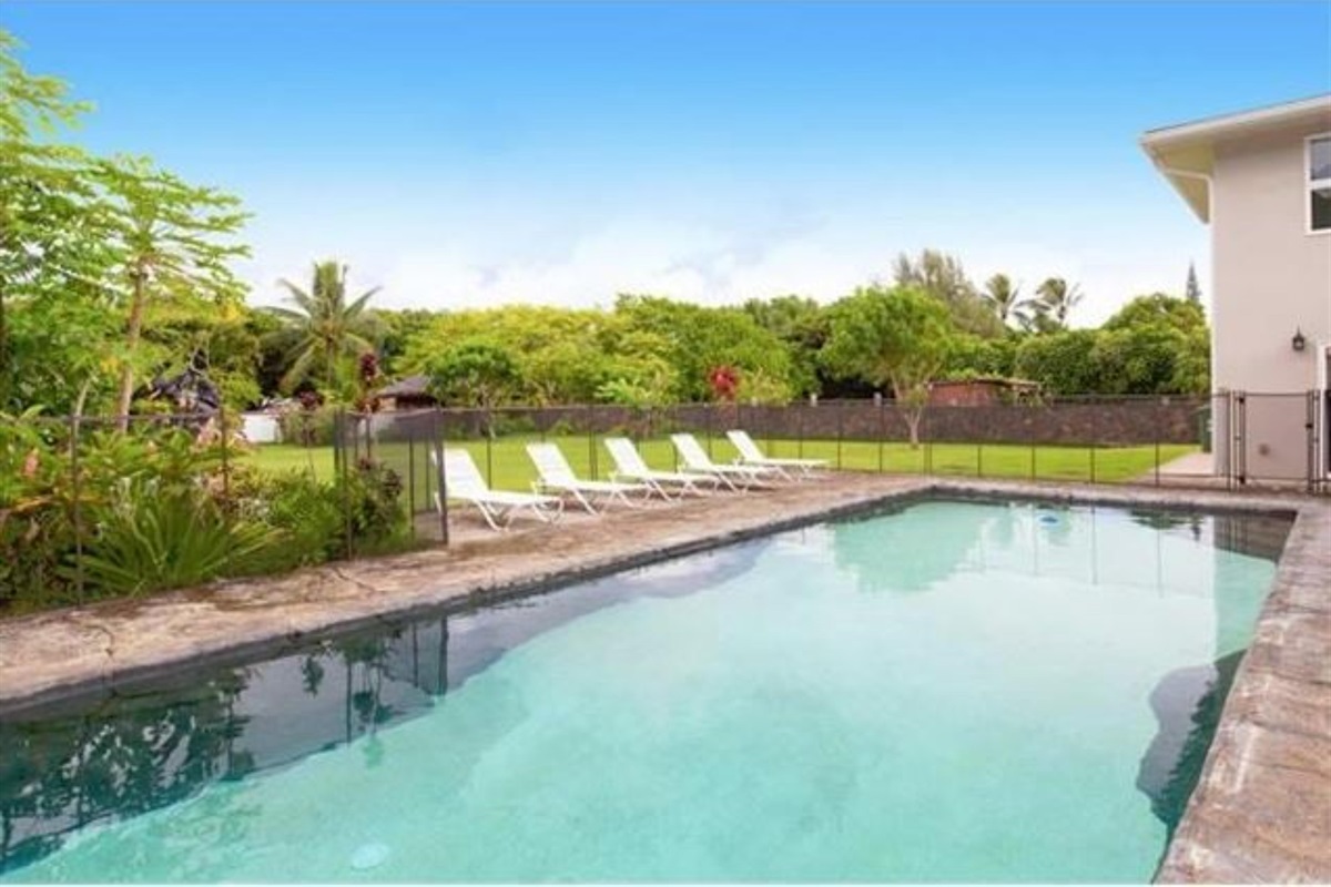 Crystal-clear pool, sun-kissed lounge chairs, and lush greenery invite relaxation