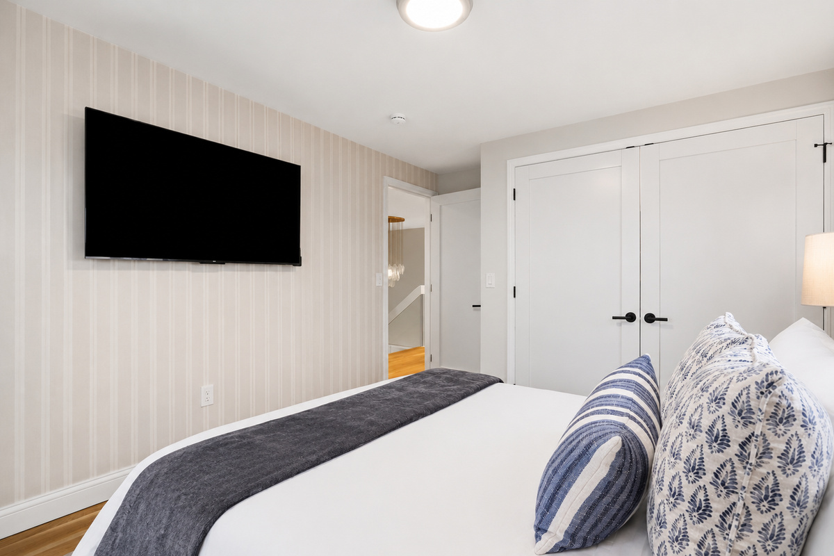 This bright and cozy bedroom features a comfortable bed, soft neutral tones, and large windows that fill the space with natural light for a relaxing retreat.