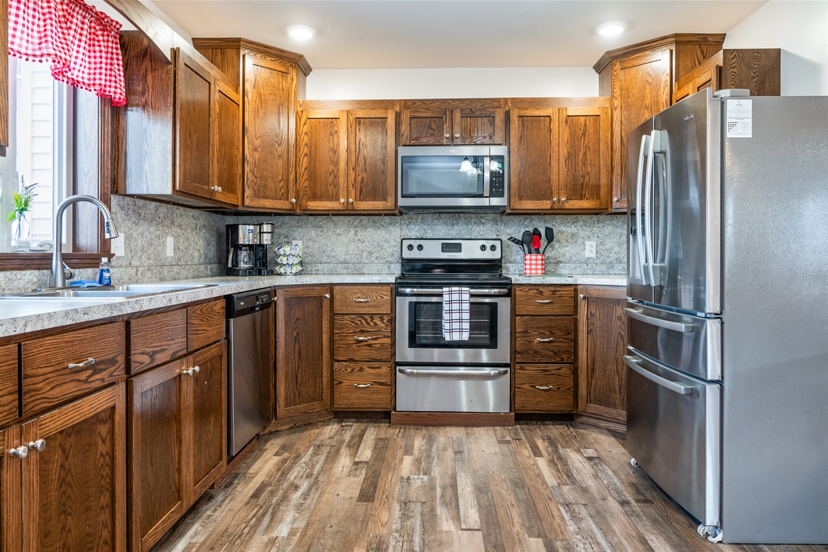 Fully equipped kitchen with stainless steel appliances and warm wood cabinetry.