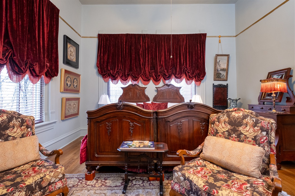 Primary sleeping area with tall windows, custom drapery, and classic Victorian charm.