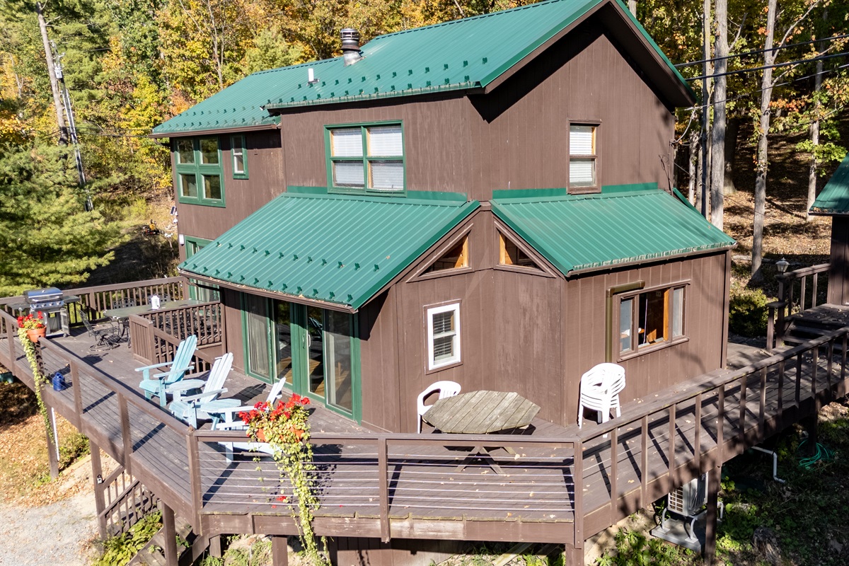 Close front view of the cabin with green roof and expansive deck for relaxing.