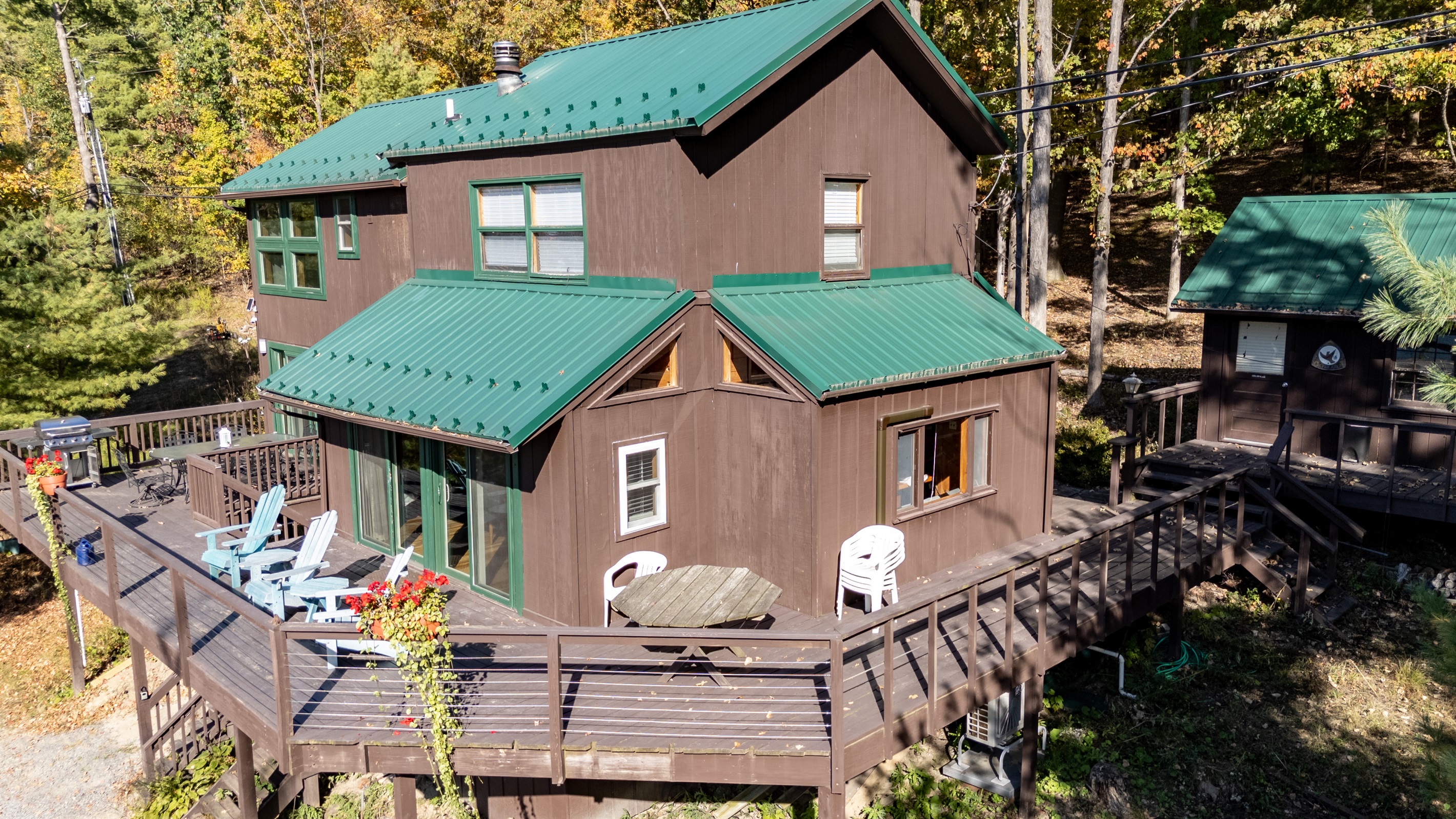 Close front view of the cabin with green roof and expansive deck for relaxing.