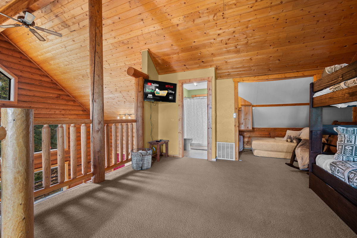 Loft entertainment area with TV, bunk sleeping, and cozy lounge space.