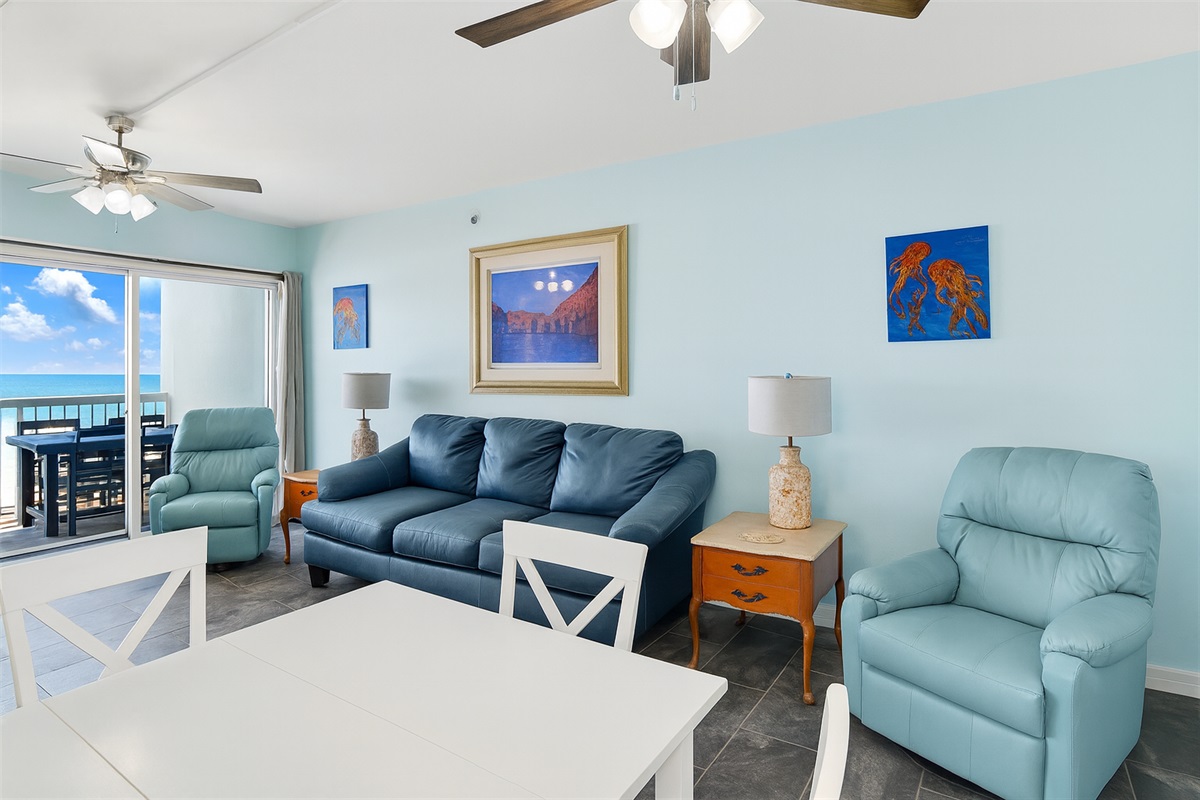 Living room with wall mounted smart TV, 2 ceiling fans, leather sleeper sofa, 2 leather rocker recliners and balcony access with breathtaking view