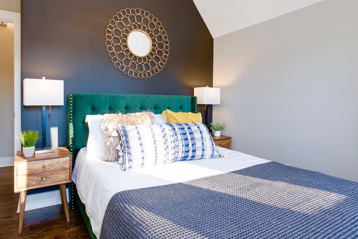 - Drift off in a room that blends bold design with soft, cozy comfort - Plush green headboard, layered pillows, and warm lighting set a calming vibe - Eye catching accents and modern decor make this the ultimate recharge zone