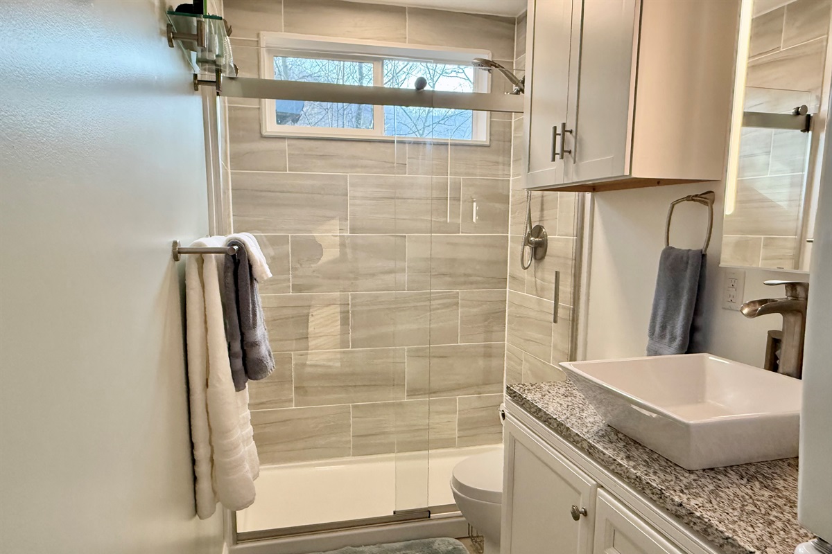 Fresh, clean, and thoughtfully designed. The bathroom features a tiled walk-in shower, vanity with sink, and modern finishes- plus a convenient front-loading washer and dryer to make longer stays easy and comfortable.