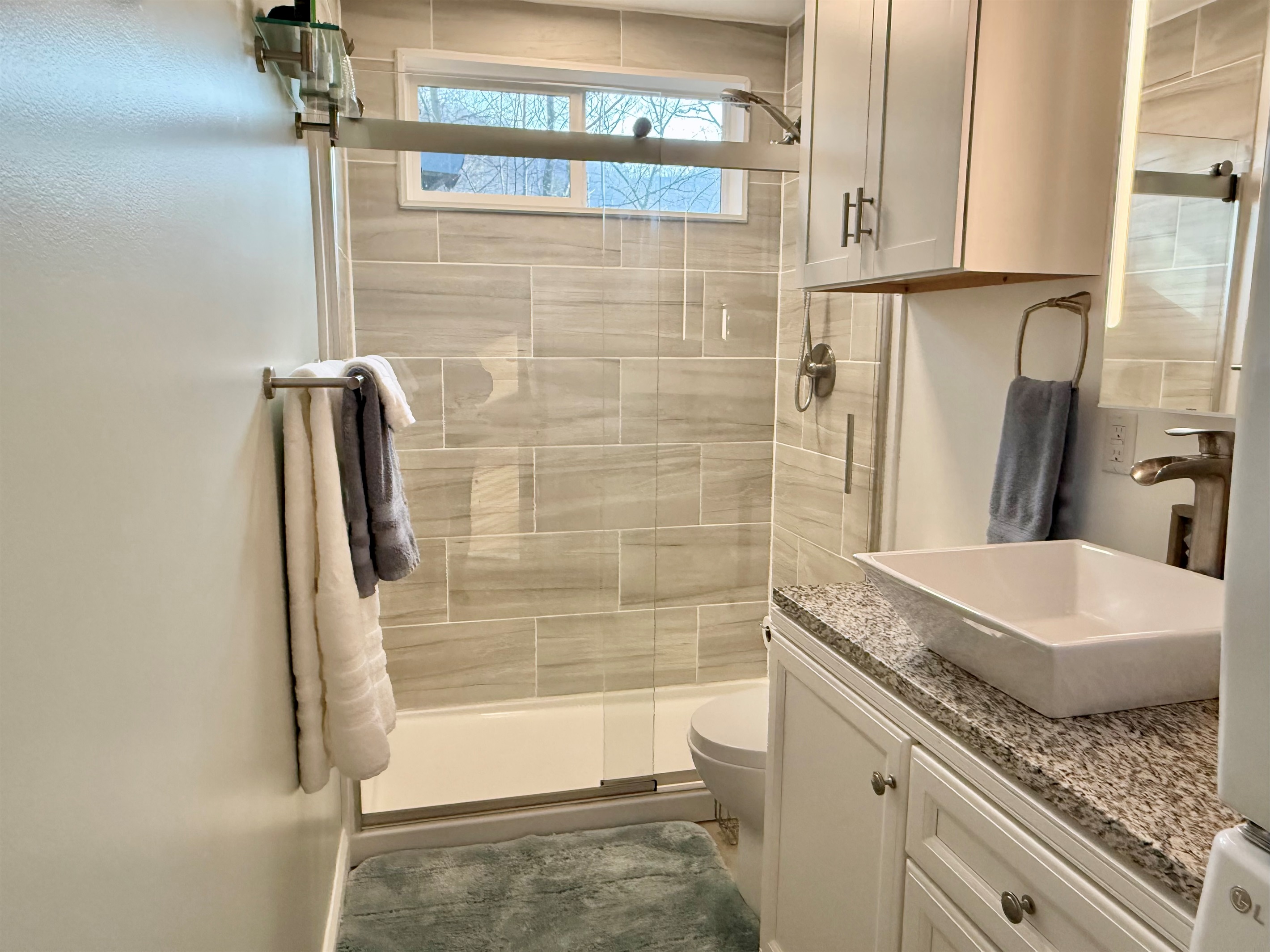Fresh, clean, and thoughtfully designed. The bathroom features a tiled walk-in shower, vanity with sink, and modern finishes- plus a convenient front-loading washer and dryer to make longer stays easy and comfortable.